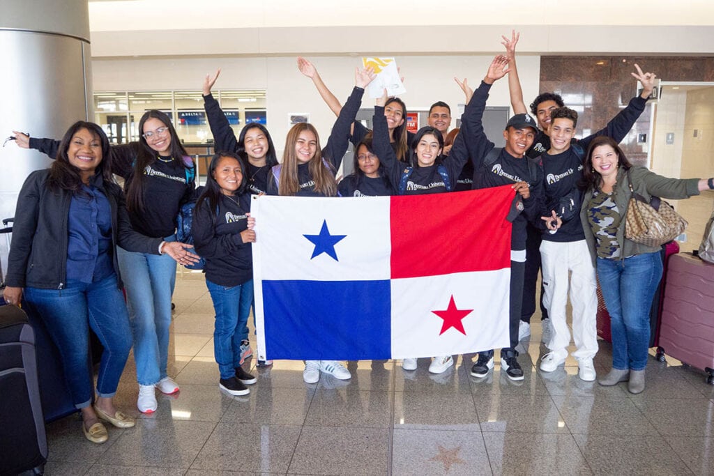 Second cohort of students from Panama posing at the airport holding Panamanian flag