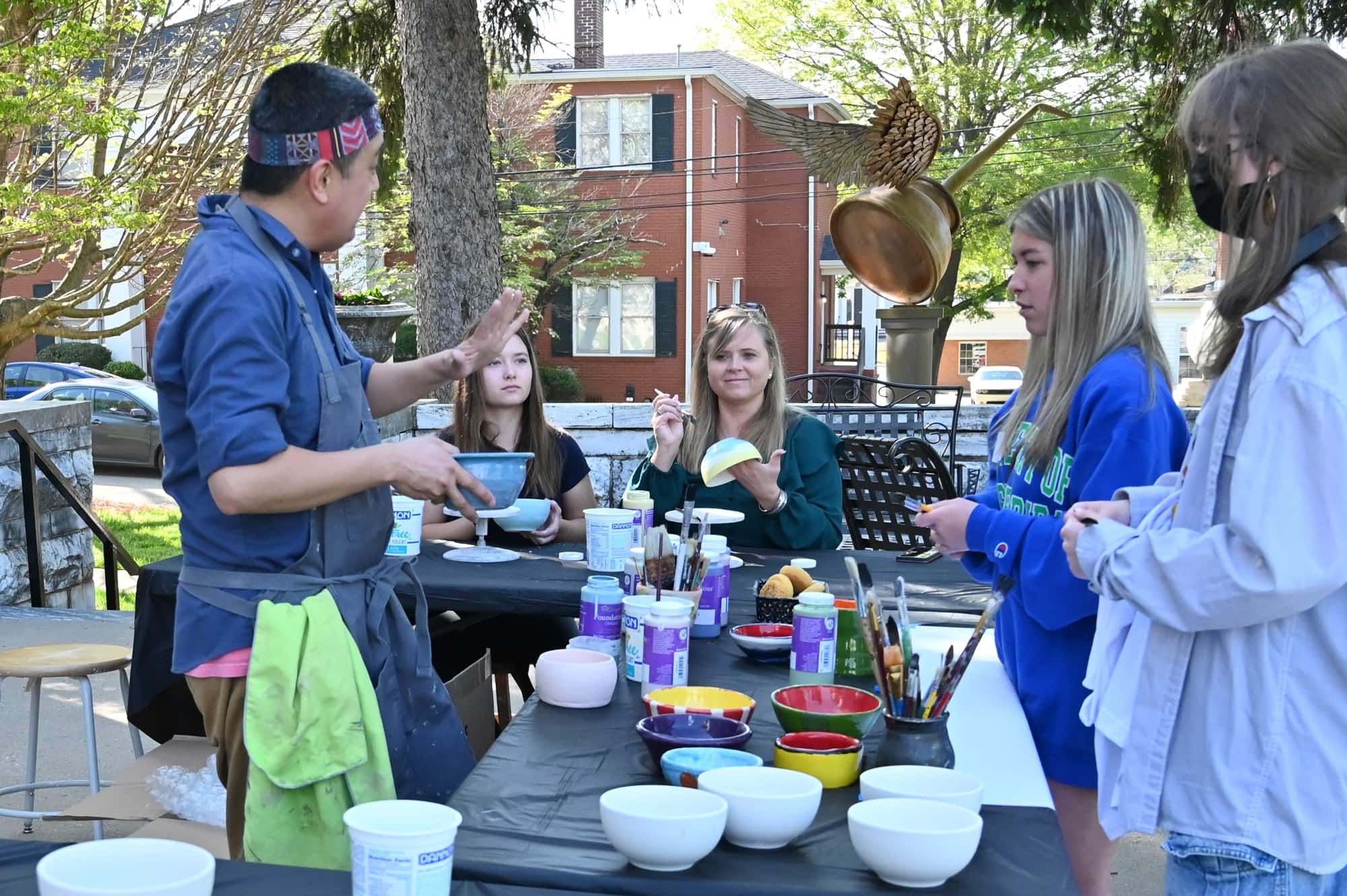 Studio arts program director Huy Chu assists participants with pottery glazing.