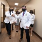 students in a hall wearing white coats