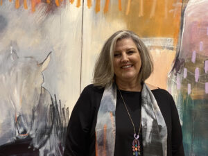 Gena Brodie Robbins stands in front of one of her abstract paintings