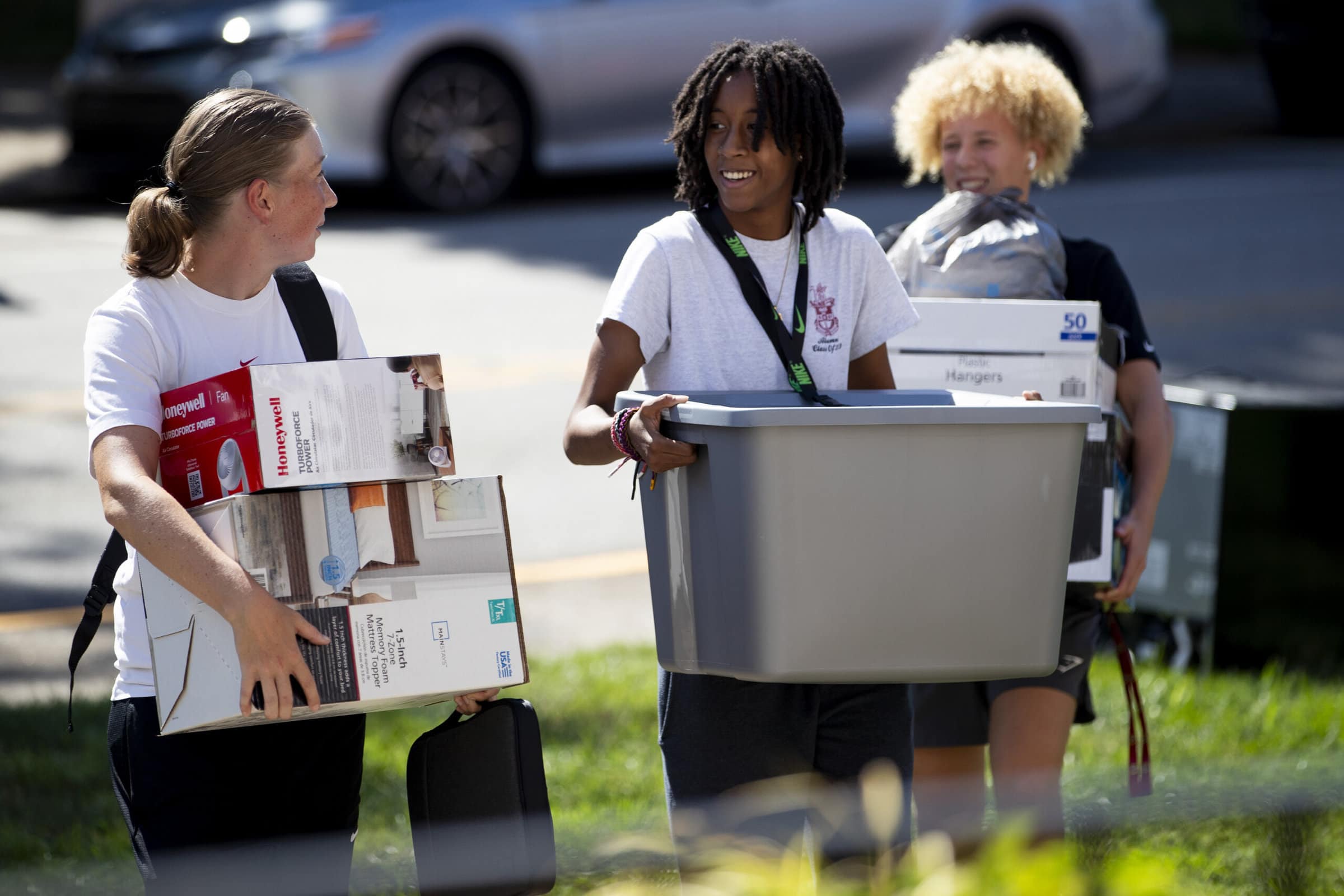 Students moving in carrying boxes and bins.