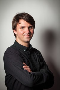 Chris Boyko, with his arms crossed in front of a grey background