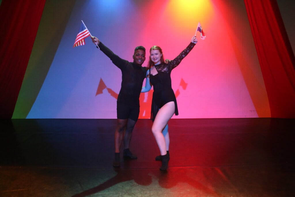 A Panamanian student and a Brenau student pose on stage together with each country's flag.