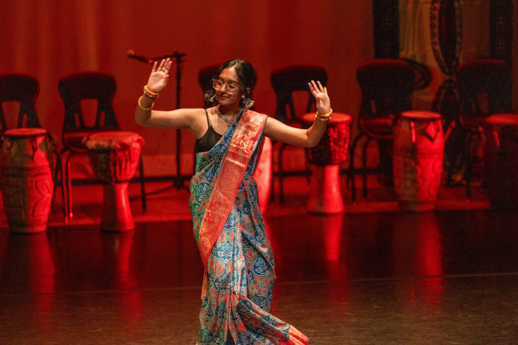 A high school student performs a traditional east Asian dance in a sari.