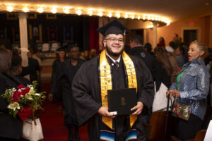 A nursing graduate walks out of Pearce Auditorium with his diploma