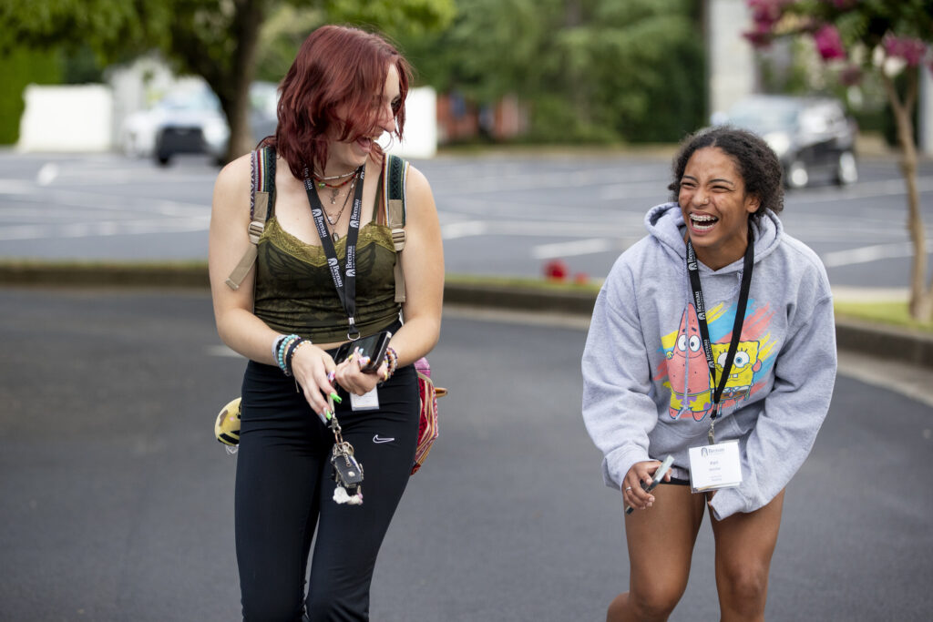 Two incoming students laugh with each other in the library parking lot