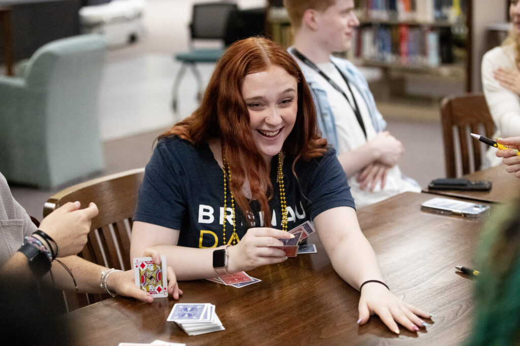 A redheaded female student plays a game of cards