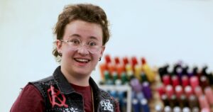 A student smiles at the camera inside Brenau's costume shop