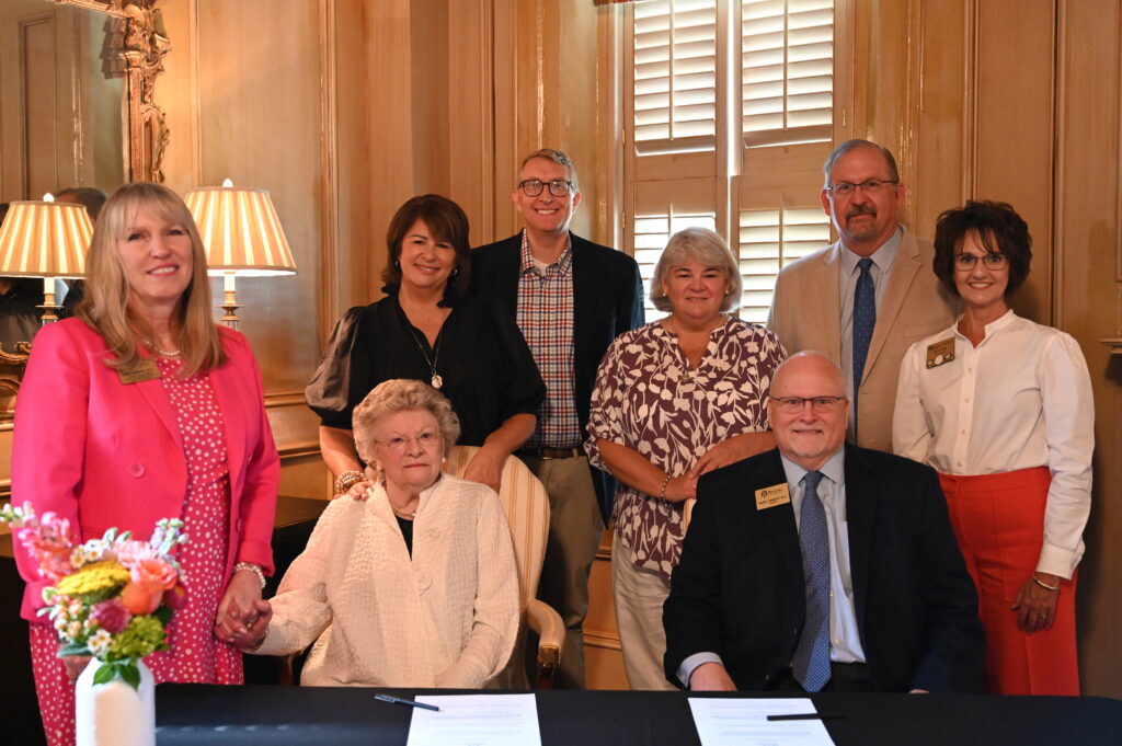 Debra Dobkins, Anna Jacobs, Matt Thomas, Chris Fitzgerald, Mike Smith, Jody Wall, Dotty Alexander (seated) and David Barnett (seated) at the signing ceremony.