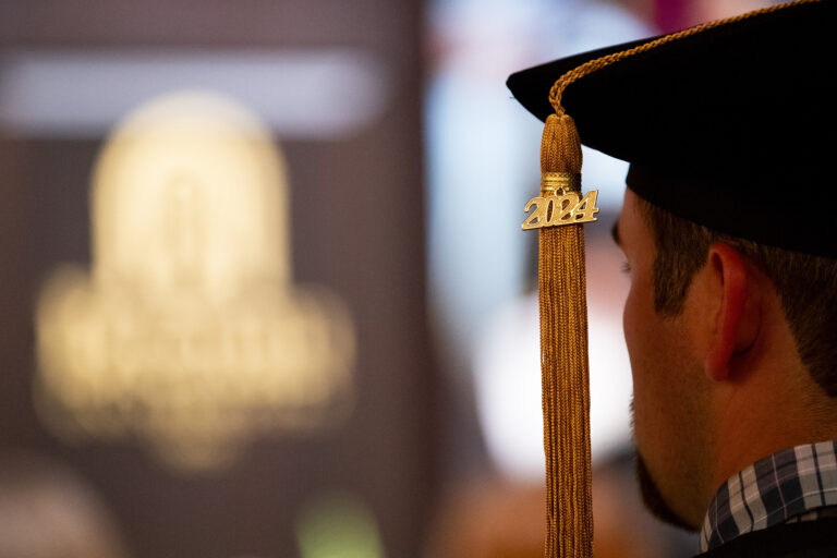 A doctoral graduate's tassel that reads 2024, with the Brenau logo in the background